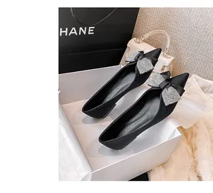 Nahaufnahme der schwarzen spitzen flachen Schuhe mit Strass-Schleife in einer Geschenkbox
