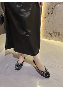 Elegant black flats featuring a sparkling rhinestone bow and stylish metallic studs.