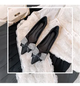 Detailansicht eleganter schwarzer flacher Schuhe mit einer glitzernden Schleife aus Strass.