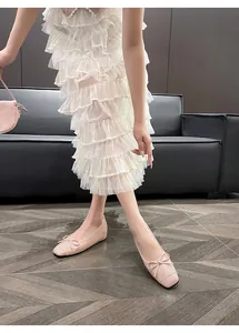 Close-up view of elegant pink leather ballet flats with bow detail worn by a model.