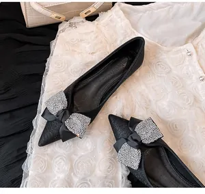 Detailaufnahme von schwarzen spitzen Ballerinas mit funkelnder Strass-Schleife.