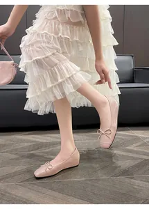 Detail of pink patent leather ballet flats with bow, vintage French style on feet.