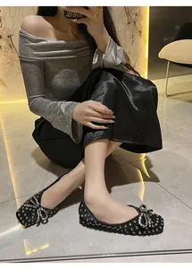 Close-up view of sparkling black rhinestone flats with a bow detail on feet