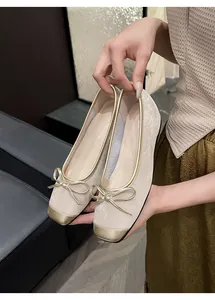 Close-up of beige French retro flats featuring gold trim and an elegant bow detail