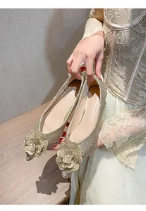 Close-up of gold glitter wedding flat shoes with elegant floral detail on pointed toe