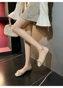 Close-up of elegant beige flat shoes with sparkling rhinestone bow detail on model