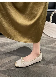 Detailed view of French vintage beige flat shoe featuring golden toe cap and bow detail