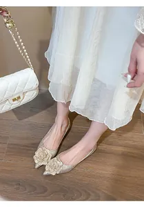 Close-up view of elegant gold glitter pointed flats featuring large flower embellishments