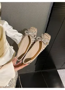 Close-up of elegant apricot flat shoes with sparkling rhinestones and a delicate bow