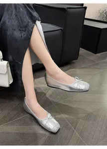 Close-up of French retro silver flat shoes with bow knot on model's feet.