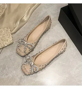 Close-up of elegant champagne flat shoes featuring sparkling rhinestone bows and accents.