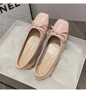 Close-up of pink patent leather ballet flats with a delicate bow and square toe.