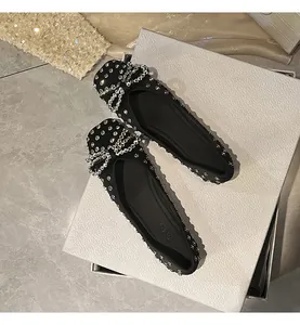 Elegant black women's flat shoes featuring a sparkling rhinestone bow and all-over studs.