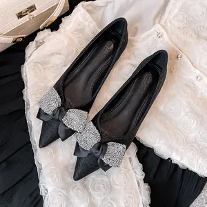 Elegante schwarze spitze Ballerinas mit einer dekorativen, funkelnden Strass-Schleife.