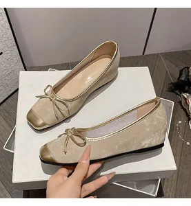 Champagne leather ballet flats featuring elegant gold toe caps and decorative bows