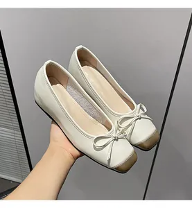 Detailed shot of French retro cream leather flat shoes featuring a bow tie and brown toe