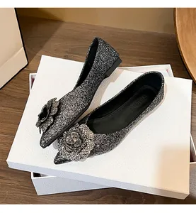 Close-up of shimmering silver glitter flat shoes with a large camellia flower