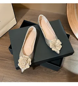 Detailed top view of gold and silver glittery pointed-toe flat shoes with flower ornament