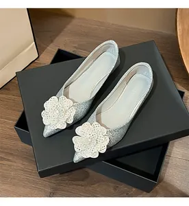 Detailed view of silver glitter wedding flats with rhinestone flower ornament