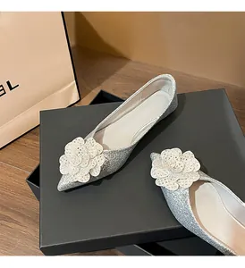 Detailed macro view of silver pointed flat shoes featuring a glitter camellia flower decor