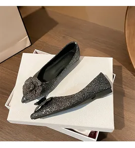 Close-up of elegant dark silver glitter pointed-toe flats with large decorative flower