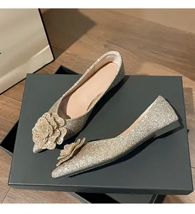 Detailed view of gold glitter flat wedding shoes with an elegant floral ornament.