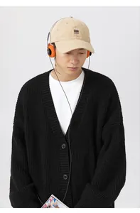 Dettaglio di un cardigan nero in maglia pesante con scollo a V e trama a costine