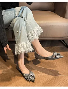 Close-up of elegant silver glittery pointed-toe flats with sparkly rhinestone bow detail.