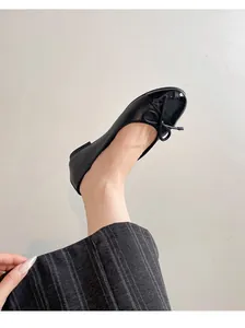 Detailed shot of elegant black ballet flats with a bow and patent leather toe cap