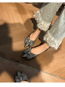 Close-up of glittering ballet flats with rhinestone bow on pointed toe