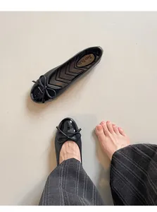 Detailed view of black French style ballet flats with bow and patent toe