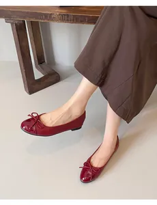 Detailed macro view of elegant burgundy patent leather ballet flats with bow decoration