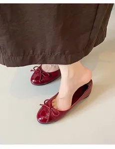 Detailed close-up of burgundy patent leather ballet flats with elegant bow decoration
