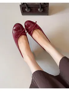 Close-up detail of red French-style ballet flats featuring a patent toe and bow