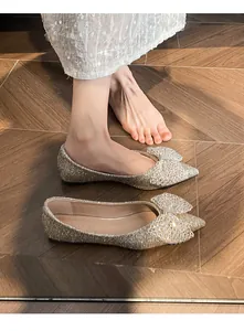 Close-up of gold sequin flat shoes with sparkling rhinestone bow detail for bridal wear