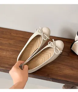 Detail view of off-white ballet flats with glossy finish and delicate bow detail