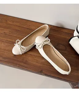 Close-up of beige round-toe flat shoes with elegant bow detail on a wooden bench
