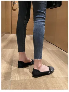 Stylish women's black square toe flat shoes with pearl decorations worn on feet