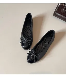 Detail view of black French style ballet flats with elegant bow and glossy toe cap