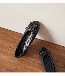 Detailed macro view of black ballet flats featuring a bow and patent leather toe