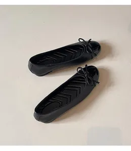 Elegant black ballet flats featuring a round toe and delicate bow detail on a neutral floor