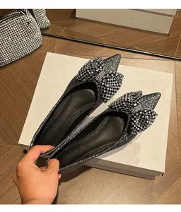 Detail view of silver glitter flat shoes featuring a sparkling rhinestone bow.