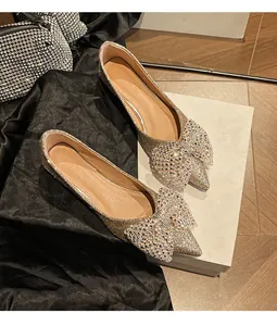Elegant gold glitter pointed-toe flats featuring a large sparkling rhinestone bow.