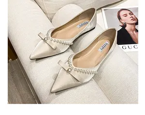 Detailed view of beige pointed-toe flats with elegant pearls and bow embellishments