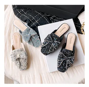 Detailansicht von funkelnden Pailletten-Mules mit eleganter Schleifendekoration.