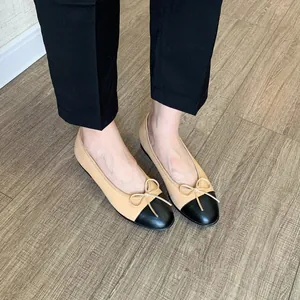 Primer plano de elegantes bailarinas bicolor en beige y negro con un delicado lazo decorativo
