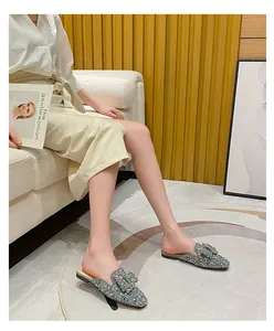 Model wearing sparkling rhinestone pointed-toe flat mules in an indoor setting