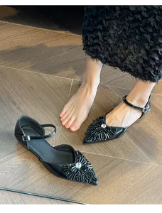 Close-up detail of black pointed-toe flat sandals featuring elegant rhinestone and bead embellishments