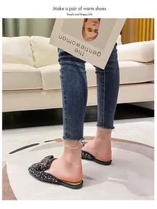 Detail view of black rhinestone pointed-toe mule shoes worn with denim jeans at home