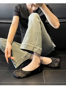 Elegant black Tabi-toe ballet flats with bow detail shown on a model sitting down